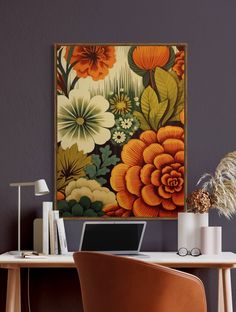 a laptop computer sitting on top of a wooden desk next to a flower covered wall