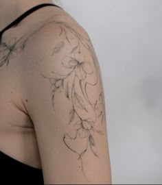 the back of a woman's shoulder with flowers and leaves on her left arm