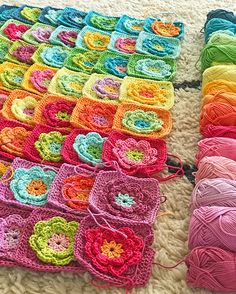 several crocheted squares and balls of yarn laid out on the floor, all in different colors