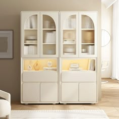 a white cabinet with glass doors in a living room next to a chair and table