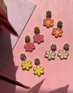 Beautiful, playful earrings with brightly coloured daisies. The perfect feel-good earring!Hand beaded, each pair of earrings takes approximately four hours to create, and is bright, bold and fun!I’ve paired the daisies with bright colourful glass crystals to make them even more of a statement pop of colour.Choose from:hot pink with yellow crystalssunkissed orange with lime crystalstraditional white with clear crystalsor bright yellow with lilac crystals.I designed the FLOWERS collection to add a Daisy Earrings, Bead Work Jewelry, Beaded Animals, Handmade Jewelry Diy, Delica Beads, Floral Jewellery, Brick Stitch, Bead Jewellery, Matching Necklaces