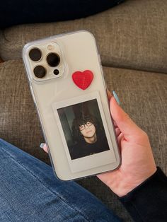 a person holding up an iphone case with a heart on the back and a photo attached to it