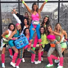 a group of women posing in front of a building with their arms up and legs crossed