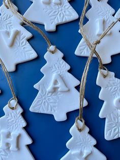 white ceramic ornaments are hanging from twine on a blue tablecloth with twine