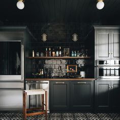 a kitchen with black and white tile flooring, dark colored cabinets and stainless steel appliances