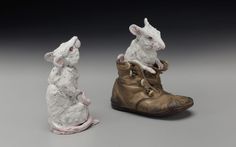 two ceramic mice sitting on top of a pair of shoes, one in the shape of a boot