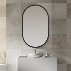 a bathroom with a sink, mirror and tiled wall behind the countertop in grey tones