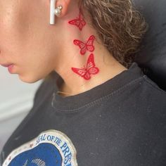 a woman with red butterfly tattoos on her neck and behind her ear is a black t - shirt