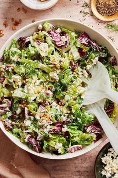 a salad with lettuce, radishes and nuts in a white bowl