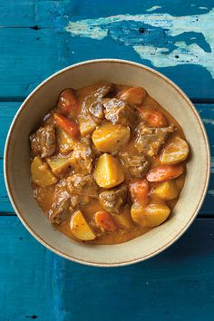 a bowl filled with stew on top of a blue table