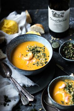 two bowls filled with soup next to a bottle of wine