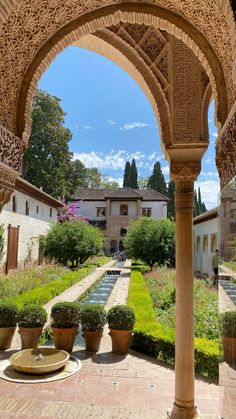 an outdoor courtyard with potted plants and water fountain in the center, surrounded by greenery