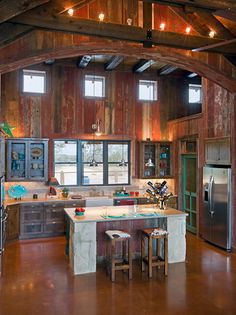 an open kitchen area with wooden walls and ceiling beams is shown in this rustic style home