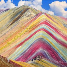 people walking up the side of a hill covered in colorfully colored hills