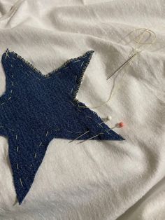 a close up of a blue star on a white shirt with some thread and scissors