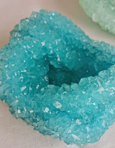 two pieces of blue glass sitting on top of a white table next to each other