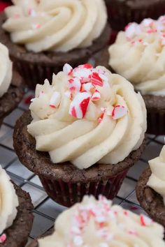 cupcakes with white frosting and sprinkles on a cooling rack