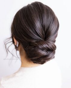 a woman's hair in a low bun is shown from the back, with long dark brown hair