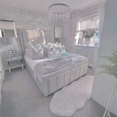 a large white bed sitting in a bedroom next to a window