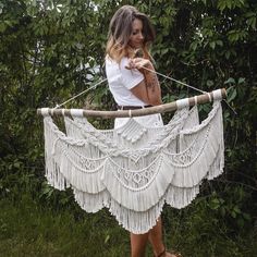 a woman is holding up a white piece of art made out of string and wood