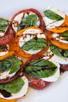 a white plate topped with sliced tomatoes and mozzarella