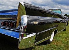 an old black car parked on top of a lush green field