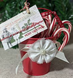 a red bucket filled with candy canes on top of a counter next to a christmas card