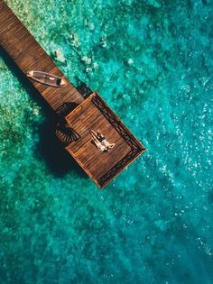 an aerial view of a pier in the ocean with two people laying on it,