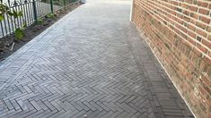 a brick walkway between two buildings next to a fence