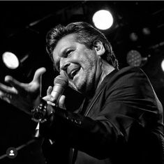 a black and white photo of a man singing into a microphone