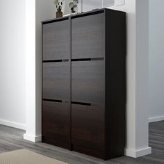 a tall wooden cabinet sitting next to a white wall in a room with hardwood floors