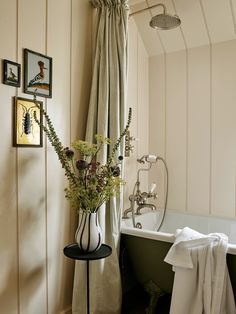 there is a vase with flowers in it next to a bathtub and towel rack