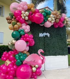 a pink flamingo balloon arch decorated with gold, green and pink balloons