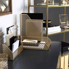 a black desk topped with lots of gold and silver items next to a shelf filled with books