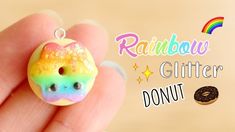 a rainbow doughnut with sprinkles on it being held in someone's hand