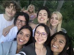 a group of young people taking a selfie in front of some trees and bushes