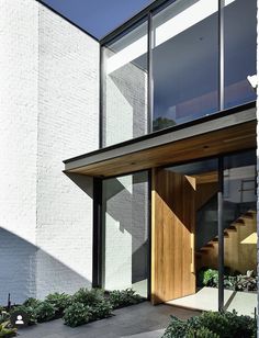 the entrance to a modern home with wood and white brickwork on the outside wall