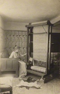 an old black and white photo of a woman sitting in front of a loom