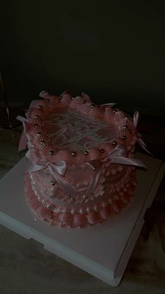 a large pink cake sitting on top of a white tablecloth covered tray with ribbon