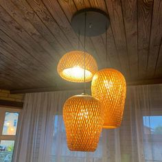 three yellow lights hanging from the ceiling in a room with wood paneling and curtains