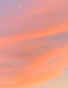 an airplane flying in the sky at sunset with a half moon above it and some clouds