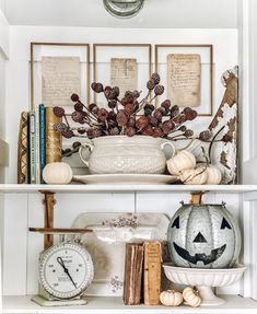 a white shelf with pumpkins, books and other items on it's shelves