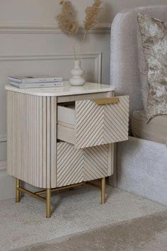 a white and gold side table next to a couch