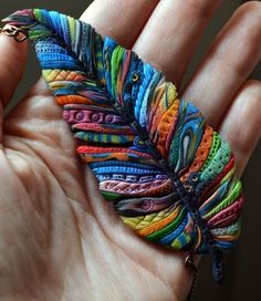 a colorful feather brooch sitting on top of someone's hand