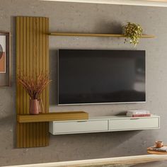 a flat screen tv mounted to the side of a wall next to a vase with flowers