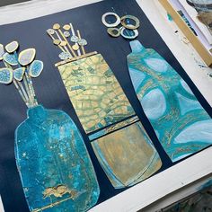 three blue vases with flowers in them are on a piece of paper and some scissors