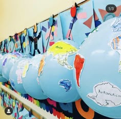 a row of blue balloons with different maps on them hanging from a wall in a hallway