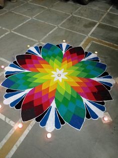 a colorful flower on the ground surrounded by candles