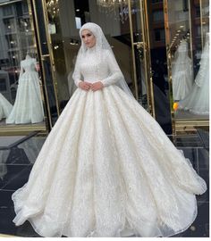 a woman standing in front of a store window wearing a white wedding dress and veil