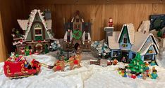 a display case filled with lots of christmas themed buildings and toys in snow covered ground